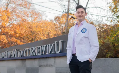 A UNE medical student poses in front of the University's entrance sign