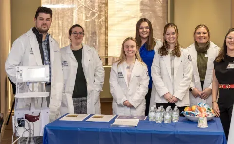 Pharmacy students pose with a UNE alum at a blood pressure clinic